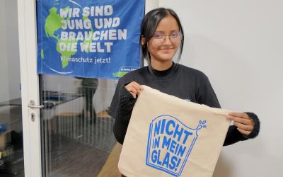 Fariha mit einem Siebdruck-Beutel vor einem Banner 