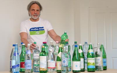 Helmut Burtscher-Schaden in einem GLOBAL 2000-T-Shirt mit allen getesteten Mineralwasserflaschen