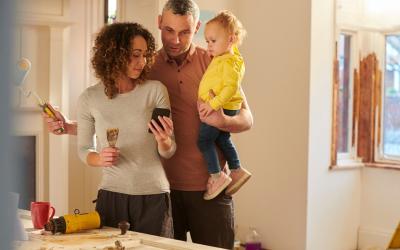 Eine Familie renoviert ihr Haus. Sie schauen sich gemeinsam etwas auf dem Handy an.