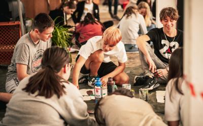 Jugendliche sitzen am Boden und malen ein Plakat