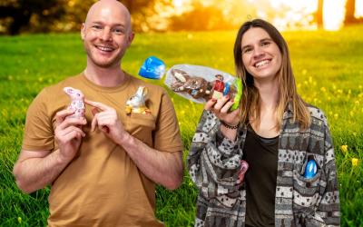 Ein junger Mann und eine junge Frau halten Schoko-Osterhasen in die Kamera und lachen