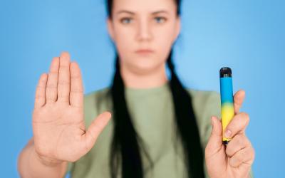 Frau hält ein E-Vape, eine E-Zigarette und macht ein Stoppzeichen mit der Hand