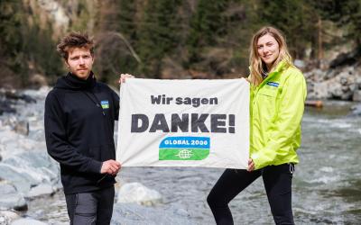 Mitarbeiter und Mitarbeiterin von GLOBAL 2000 halten Banner mit Wir sagen Danke