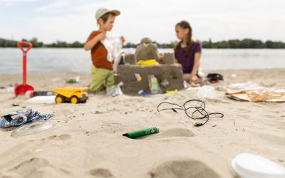 Kinder spielen im Sand, der voll mit Müll ist