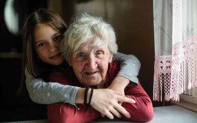 Mädchen umarmt ältere Frau von hinten