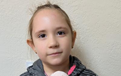 Mädchen mit grauer Jacke hält ein Stoffhasen in den Händen