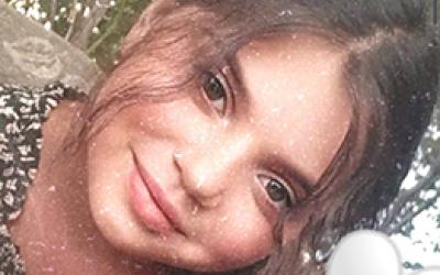 Mädchen mit Schwarz weißem Shirt und Braunen Haaren lächelt. 