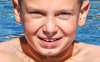 Junge mit kurzem Haar schwimmt in einem Pool