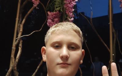 Mykyta, ein blonder Bub mit 13 Jahren, grüßt in die Kamera