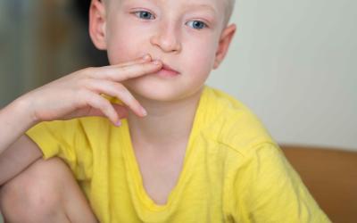 Ukrainischer Bub denkt nach, sitzt mit Papier und Stift