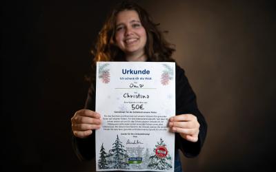 Mädchen hält glücklich Spenden-Urkunde in die Kamera