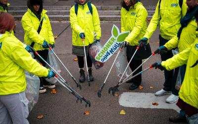 GLOBAL 2000-Freiwillige in grünen Jacken stehen im Kreis und werden Müllsammeln