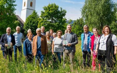 Gemeinde Göfis Mitgleider stehen auf einer Wiese und halten Nationalpark Garten Plakette