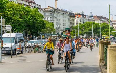 Menschen auf Fahrrädern fahren durch Wiens Innenstadt bei U-Bahn Abgang vorbei