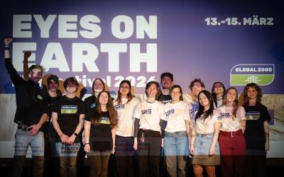 Gruppe von Menschen steht vor einer Wand mit dem Schriftzug 'EYES ON EARTH festival 2023' und dem Datum '13.-15. MÄRZ'