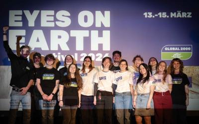 Team*Aktiv steht vor einer Wand mit dem Schriftzug 'EYES ON EARTH Festival 