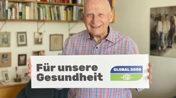 Pensionist Peter Fliegenschnee hält Schild "Für unsere Gesundheit" im Rahmen der "Dein gutes Recht auf saubere Energie"-Initiative