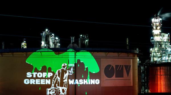 Lichtprojektion an OMV: Mann im Anzug malt OMV grün an