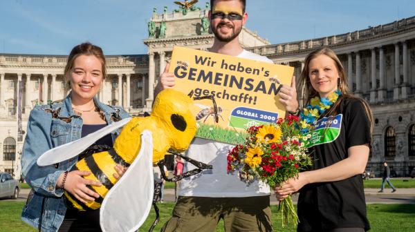Aktivist:innen mit Biene und Schild vor Nationalbibliothek