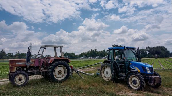 Ein alter und ein neuer Traktor stehen am Feld