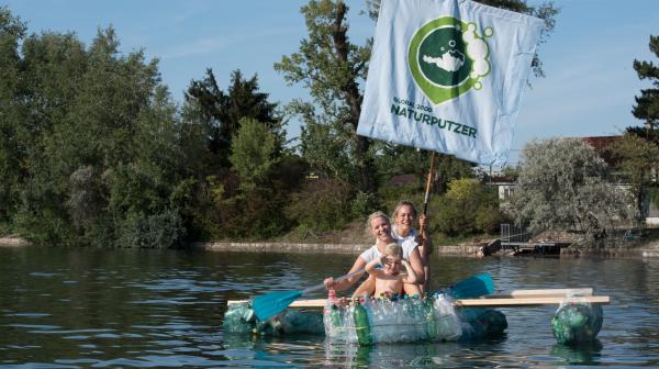 NaturPutzer in einem Boot aus Plastikmüll für den Umweltschutz