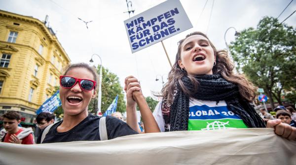 Zwei Aktivistinnen bei einer Demo, im Hintergrund der GLOBAL2000 Slogan "Wir kämpfen für das Schöne"