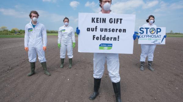 Global 2000 Aktivist*innen auf Feld mit Protest "Kein Gift auf unsere Feldern" und "Stopt Glyphosat"