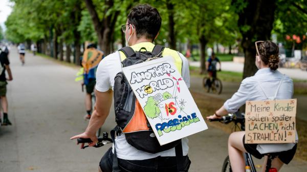 Aufnahme von zwei DemonstrantInnen mit Protestschildern am Rücken "Another World is possible" 