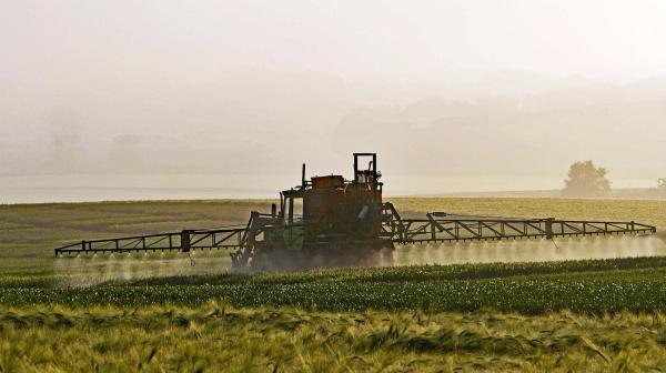 Traktor sprüht Pestizide auf Feld