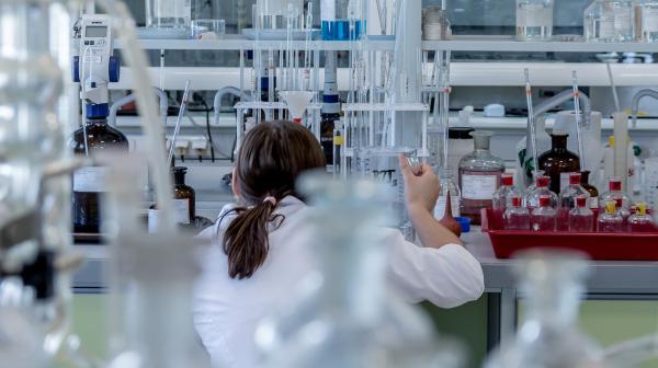 Frau hantiert mit Chemikalien im Labor