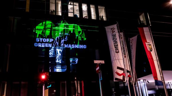 "Stopp Green Washing" Projektion an einer Hausfassade