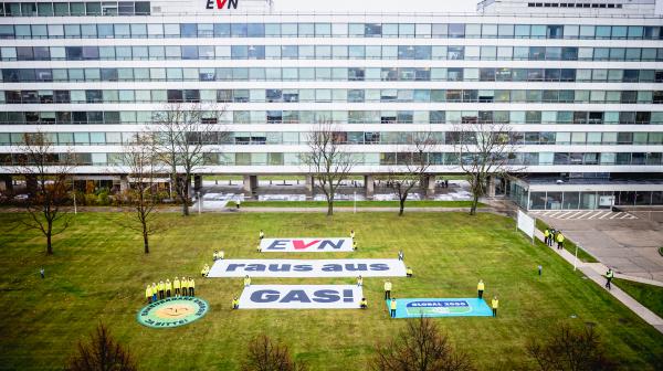 Banner mit der Aufschrift "EVN – Raus aus Gas!" liegt auf einer Wiese vor dem EVN-Hauptgebäude