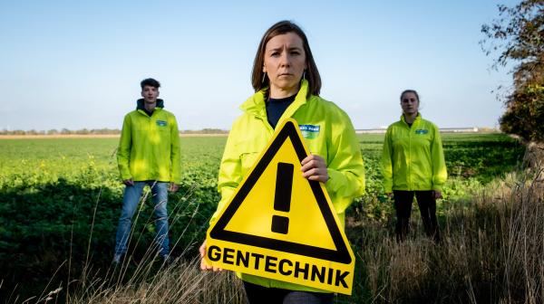 Brigitte Reisenberger, Gentechniksprecherin von GLOABAL 2000 hält  "Achtung Gentechnik"-Schild. Hinter ihr stehen zwei Aktivist:innen.