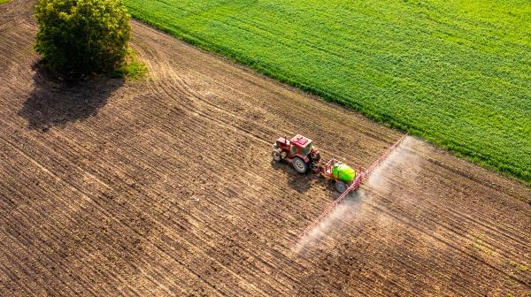Traktor sprüht Pestizide, Aufnahme von oben als Luftbild
