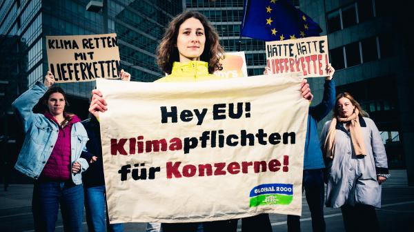 Anna Leitner hält Banner mit "Klimapflichten für Konzerne" in der Hand