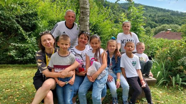 Kinder und Erwachsene sitzen für ein Gruppenfoto unter einem Baum zusammen