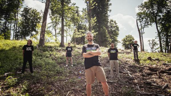 GLOBAL 2000 Mitarbeiter:innen stehen in einem abgeholzten Wald