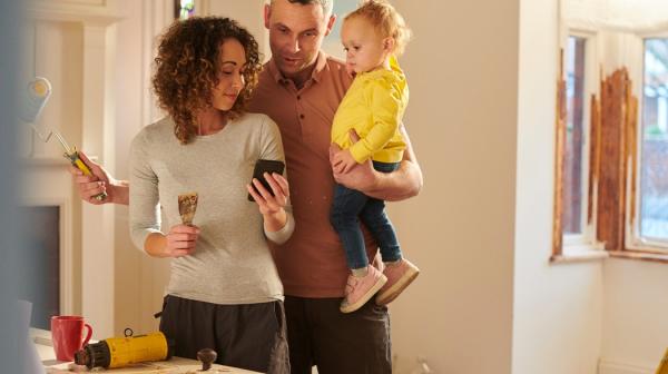 Eine Familie renoviert ihr Haus. Sie schauen sich gemeinsam etwas auf dem Handy an. 