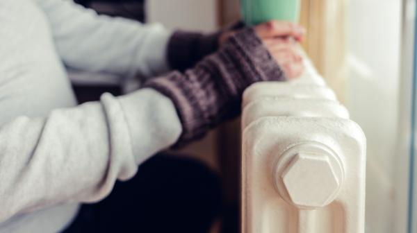 Frau wärmt sich an Heizkörper.