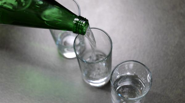 Aus einer Flasche fließt Mineralwasser in ein Glas