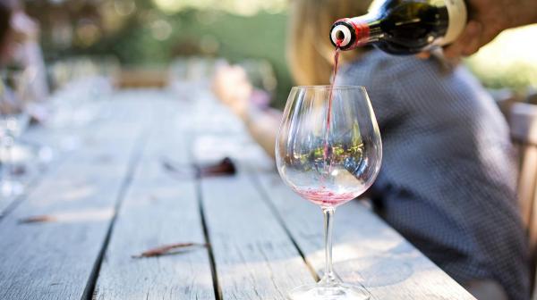 Rotwein wird in ein großes Weinglas geschenkt