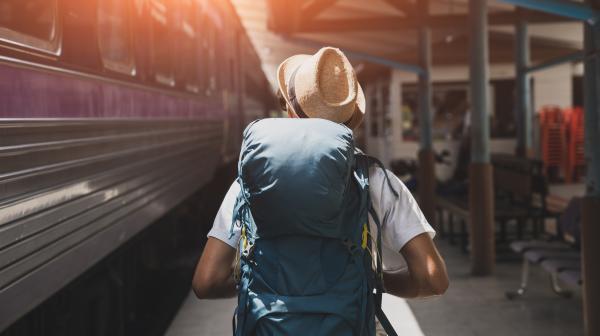 Person mit Rucksack und einfahrendem zug