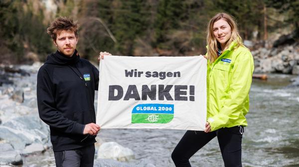 Mitarbeiter und Mitarbeiterin von GLOBAL 2000 halten Banner mit Wir sagen Danke