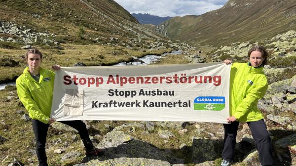 Zwei Personen von GLOBAL 2000 stehen im Platzertal und halten Banner mit der Aufschrift "Stopp Alpenzerstörung Stopp Ausbau Kraftwerk Kaunertal"
