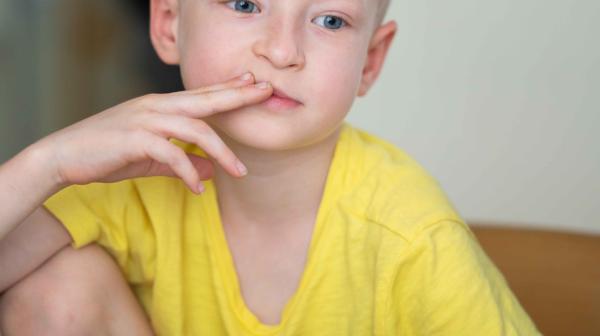 Ukrainischer Bub denkt nach, sitzt mit Papier und Stift