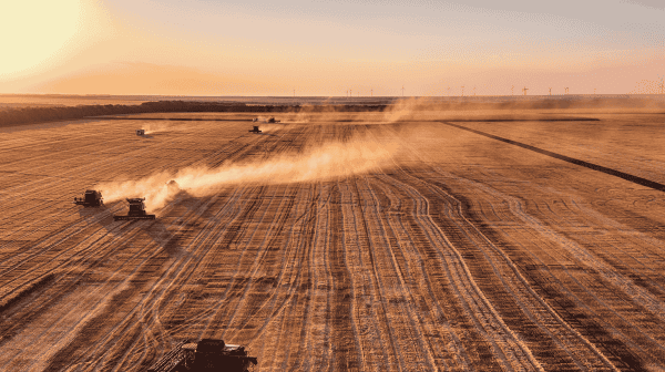 Mehrere landwirtschaftliche Geräte fahren über ein Feld über rötliche Erde