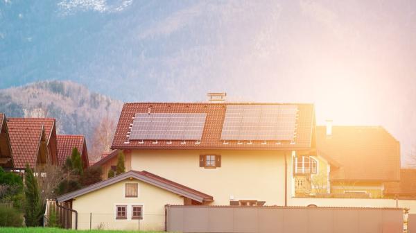 Einfamilienhaus im Sonnenuntergang. Auf den Dächern sind Solarmodule installiert.