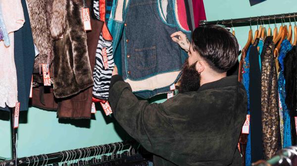 Mann sieht sich Kleidung in Secondhand-Shop an