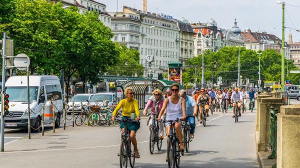 Menschen auf Fahrrädern fahren durch Wiens Innenstadt bei U-Bahn Abgang vorbei