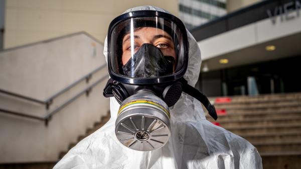Eine Frau im Strahlenschutzanzug und einer Gasmaske steht vor einem Regierungsgebäude